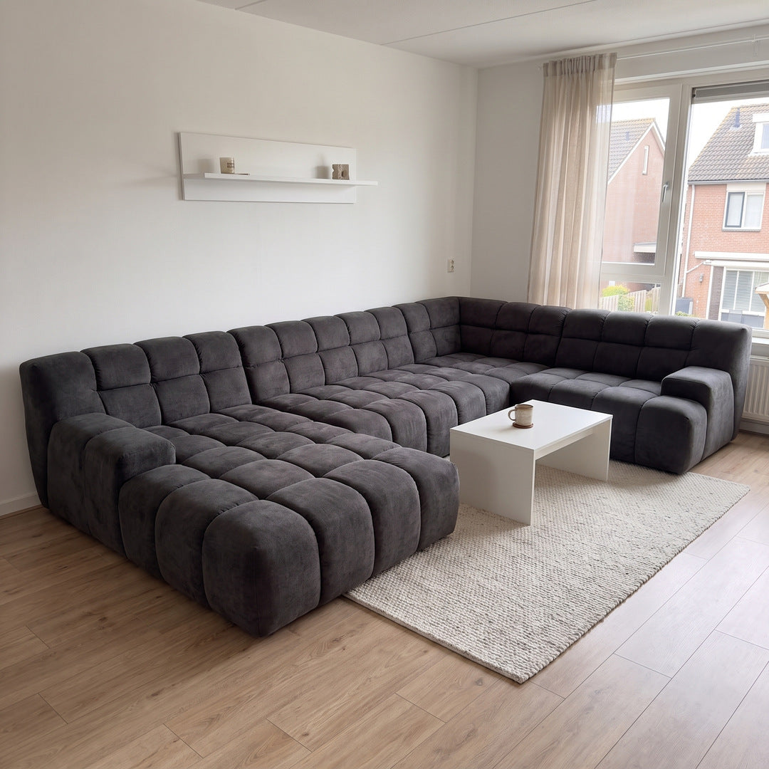 Modulares U-Sofa in Anthrazit mit Steppkissen im hellen Wohnzimmer